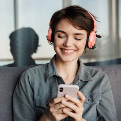 Junge Frau hört mit Kopfhörern einen Podcast